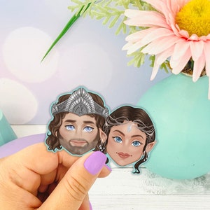 May include: Two illustrated faces of a man and woman with crowns on their heads. The man has a beard and brown hair. The woman has long brown hair and a silver crown. The faces are on a white background.