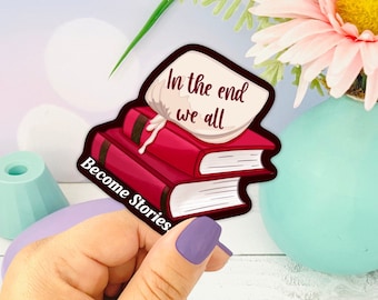May include: A sticker with a stack of red books and a white bag with the text "In the end we all Become Stories".