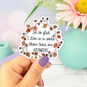 May include: A white sticker with a wreath of autumn leaves around the text "I'm so glad I live in a world where there are Octobers."