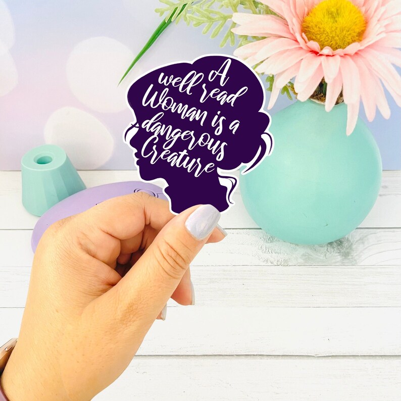 May include: A purple silhouette of a woman's head with the text "A well read woman is a dangerous creature" in white.