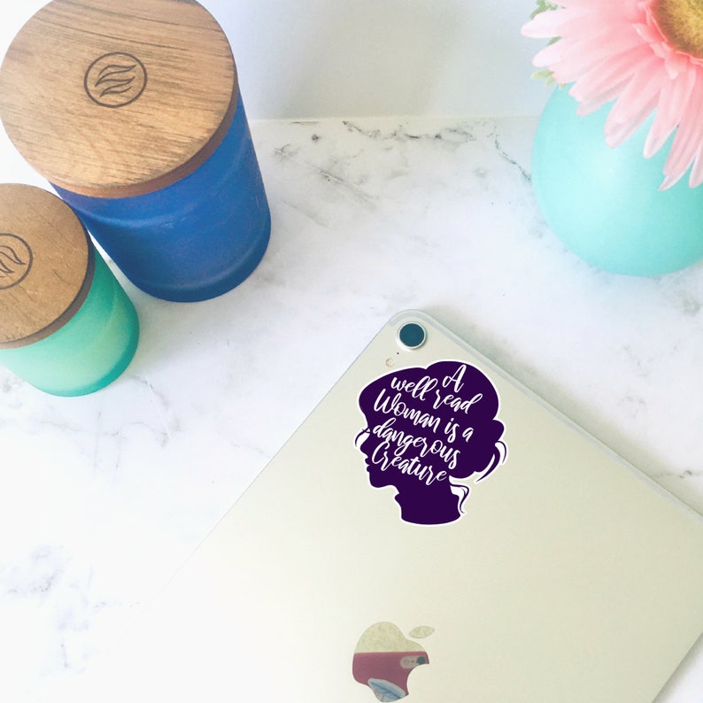 May include: A purple silhouette of a woman's head with the text "A well read woman is a dangerous creature" in white lettering.
