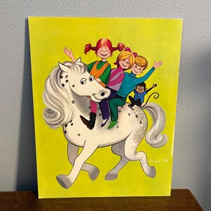 May include: A rectangular print on a bright yellow background featuring a white horse with black spots. Three children with red, blonde, and brown hair are riding the horse, accompanied by a small monkey sitting on the horse's back near the tail.