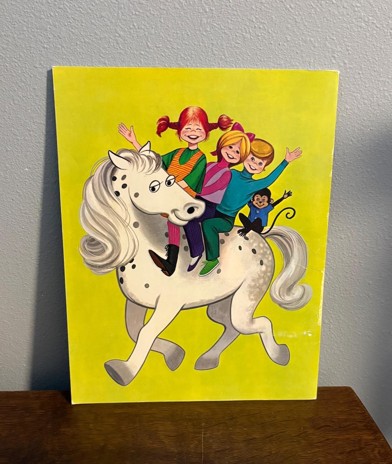 May include: A rectangular print on a bright yellow background featuring a white horse with black spots. Three children with red, blonde, and brown hair are riding the horse, accompanied by a small monkey sitting on the horse's back near the tail.