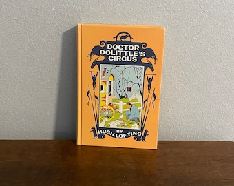 May include: A vintage hardcover book titled "Doctor Dolittle's Circus" by Hugh Lofting. The cover features an illustration of a circus scene with a man, animals, and a wagon.