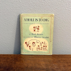 May include: Vintage children's book titled "A Hole Is To Dig" by Ruth Krauss, with illustrations by Maurice Sendak. The book has a light green cover with illustrations of children and the text "A First Book of First Definitions".