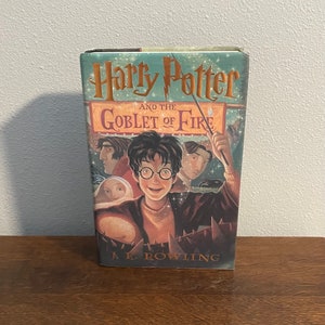 May include: A hardcover book titled "Harry Potter and the Goblet of Fire" by J.K. Rowling. The cover features an illustration of Harry Potter with a wand in his hand, surrounded by other characters from the book.