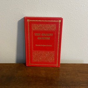 May include: A red hardcover book with gold lettering titled "The Secret Garden" by Frances Hodgson Burnett.