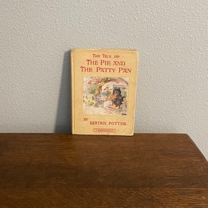 May include: A vintage book titled "The Tale of The Pie and The Patty Pan" by Beatrix Potter. The cover features a black and white illustration of a rabbit holding a pie.