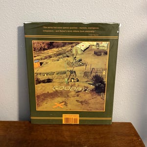 Op de afbeelding: Een boekomslag met een groene rand en een sepia-kleurige afbeelding van een militair kamp. Het woord "GOODBYE" is in witte letters gespeld. De omslag bevat ook een citaat en een streepjescode.