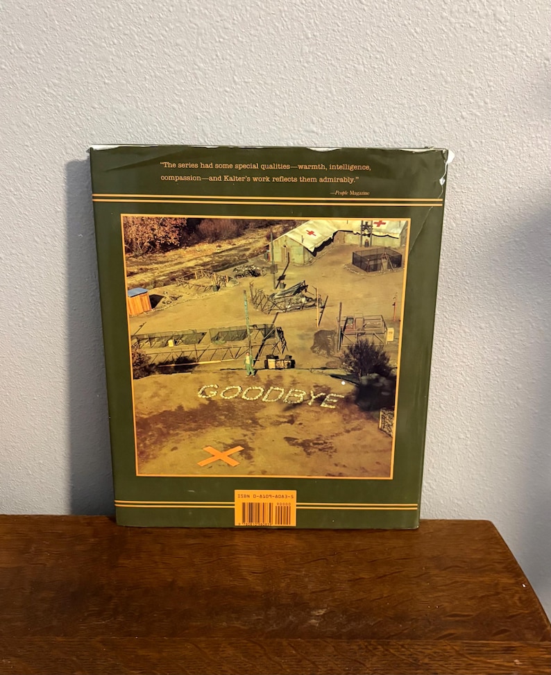 Op de afbeelding: Een boekomslag met een groene rand en een sepia-kleurige afbeelding van een militair kamp. Het woord "GOODBYE" is in witte letters gespeld. De omslag bevat ook een citaat en een streepjescode.