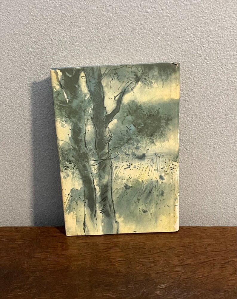 May include: A vintage book cover with a watercolor illustration of a tree and a field. The illustration is in shades of blue and green.