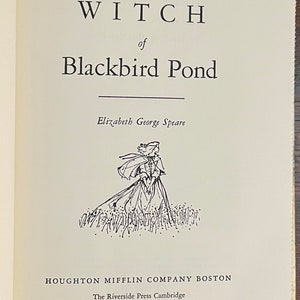 May include: The cover of a vintage book titled "The Witch of Blackbird Pond" by Elizabeth George Speare. The book cover features a black and white illustration of a woman in a long dress and cloak walking through a field of tall grass.