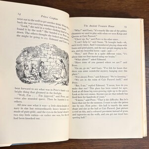 以下が含まれることがあります： テキストとイラストが掲載された開いた本。イラストは、石壁の近くにいる人々のグループを示しています。テキストには「Prince Caspian」と「The Ancient Treasure House」というタイトルが含まれています。