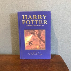May include: A blue hardcover book with the title "Harry Potter and the Goblet of Fire" in gold lettering. The cover features an illustration of a dragon breathing fire.