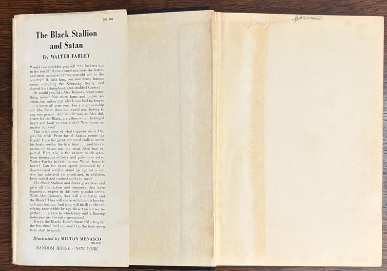 May include: Open book with the title "The Black Stallion and Satan" by Walter Farley. The book's pages are off-white with black text. The cover is black. The book is illustrated by Milton Menasco and published by Random House, New York.