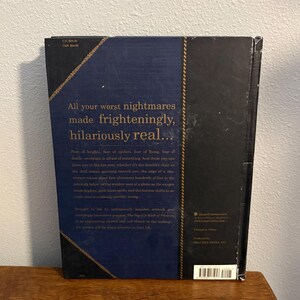 May include: A hardcover book with a dark blue cover and gold text. The title reads "All your worst nightmares made frighteningly, hilariously real..." The book has a textured spine and a decorative border.