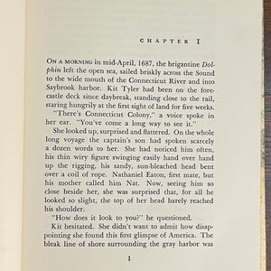 May include: A vintage book with a brown cover and gold lettering. The title of the book is "Chapter I". The text on the page describes a ship arriving in a harbor.