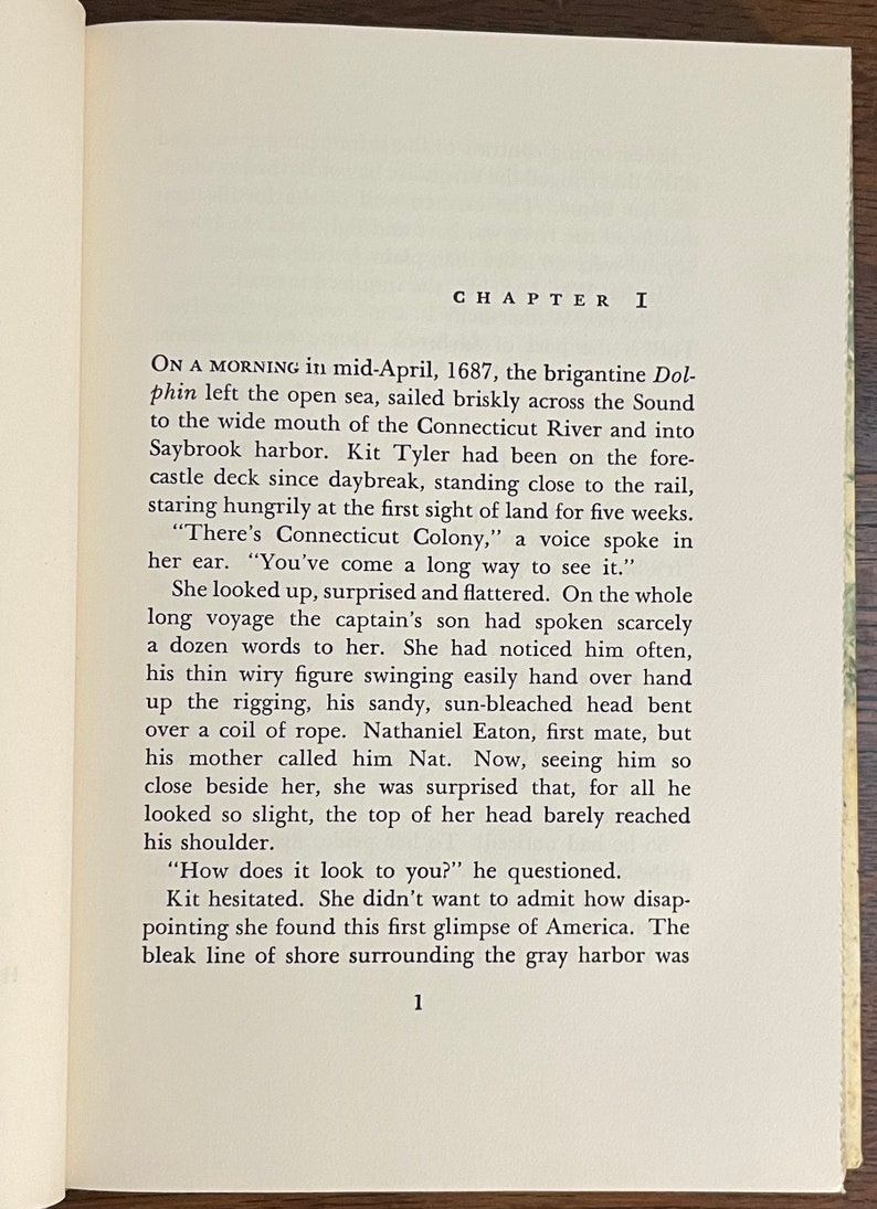 May include: A vintage book with a brown cover and gold lettering. The title of the book is "Chapter I". The text on the page describes a ship arriving in a harbor.