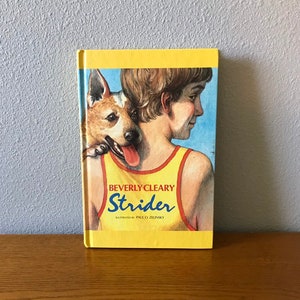 Może przedstawiać: Żółta książka w miękkiej oprawie zatytułowana "Strider" autorstwa Beverly Cleary. Okładka przedstawia ilustrację chłopca z psem.