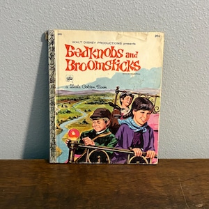 May include: A vintage Little Golden Book titled Bedknobs and Broomsticks, featuring an illustration of three children riding a brass bed frame over a landscape. The cover includes the text Walt Disney Productions presents and the price 39 cents.