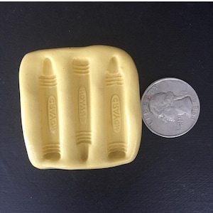 May include: Yellow silicone mold with three cavities shaped like Crayola crayons. Each cavity has the word "Crayola" embossed on the side.
