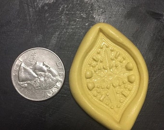 May include: A yellow silicone mold shaped like a lemon wedge with a detailed design of hearts and dots inside. The mold is about the size of a quarter.
