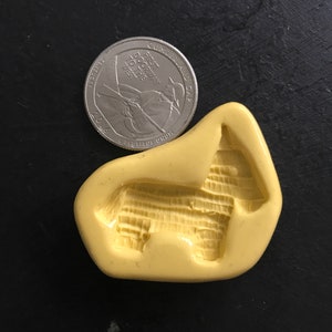 May include: Yellow silicone mold for making a pinata shaped like a donkey. The mold is about the size of a US quarter.