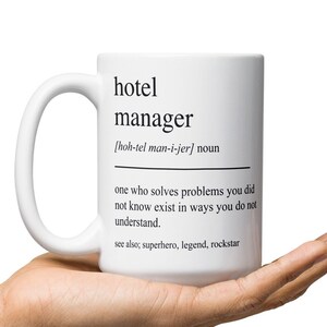 以下が含まれることがあります： 白いセラミック製のマグカップで、黒いデザインが施されています。"hotel manager [hoh-tel man-i-jer] noun one who solves problems you did not know exist in ways you do not understand. see also, superhero, legend, rockstar"と書いてあります。