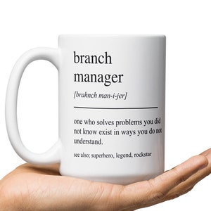 May include: White ceramic mug with a black and white definition of "branch manager" printed on it. The definition reads: "one who solves problems you did not know exist in ways you do not understand. See also: superhero, legend, rockstar."