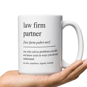May include: White ceramic mug with a black design that reads "law firm partner" and defines the term as "one who solves problems you did not know exist in ways you do not understand." The mug also includes the text "see also, superhero, legend, rockstar."