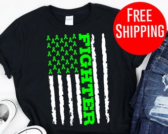 May include: Black t-shirt with a white and green American flag design. The flag is made up of green ribbons and the word "Fighter" is written vertically down the right side of the flag.