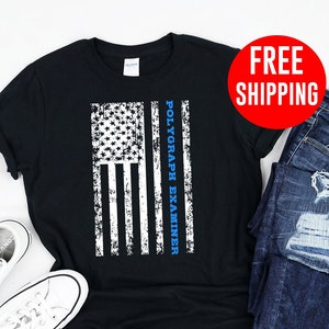 May include: Black t-shirt with a distressed American flag design and the text "Polygraph Examiner" in blue lettering.