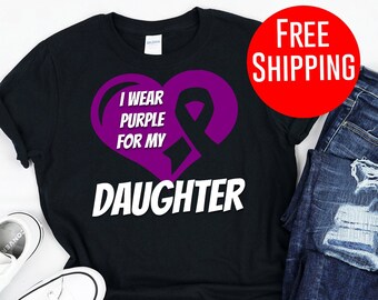 May include: Black t-shirt with a purple heart and ribbon design. The text on the shirt reads "I wear purple for my daughter".
