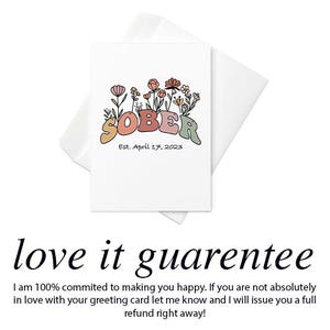 May include: A white greeting card with the word "SOBER" in colorful letters, surrounded by floral illustrations. The text "Est. April 17, 2023" is below the word. The card is inside a white envelope.