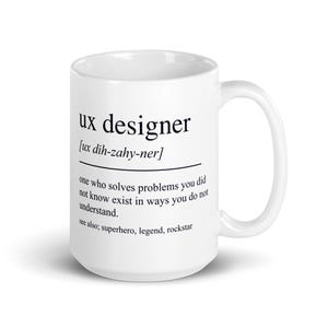 Op de afbeelding: Een witte keramische mok met zwarte tekst die een UX-designer definieert als iemand die problemen oplost waarvan je niet wist dat ze bestonden, inclusief de fonetische uitspraak en de woorden see also; superhero, legend, rockstar.
