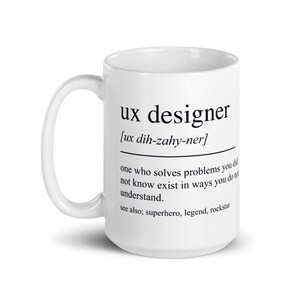 Op de afbeelding: Een witte keramische mok met de zwarte tekst "ux designer" en een definitie. De definitie bevat de uitspraak en een beschrijving van een UX-ontwerper. De mok heeft een gebogen handvat.