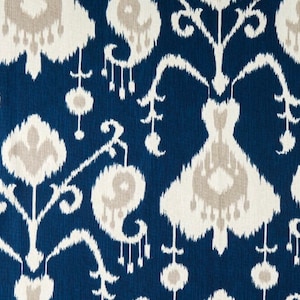 May include: A close-up of a blue and white fabric with an ikat pattern. The fabric has a white background with a blue pattern of flowers and leaves.