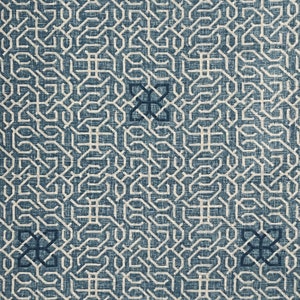 May include: A blue and white geometric pattern on a textured fabric background. The pattern is made up of repeating squares and lines.