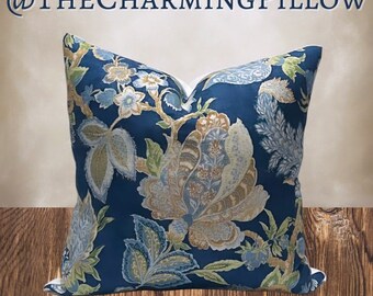 May include: A blue pillow with a floral pattern in shades of brown, blue, and green. The pillow is on a wooden surface.