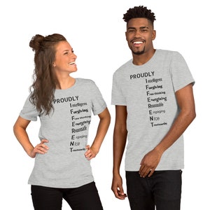 Könnte beinhalten: Zwei Personen tragen graue T-Shirts mit dem Wort "PROUDLY" und einer Liste positiver Adjektive, die vertikal geschrieben sind. Die Adjektive sind: Intelligent, Verzeihend, Freidenkend, Energiegeladen, Vernünftig, Engagiert, Nett, Vertrauenswürdig.