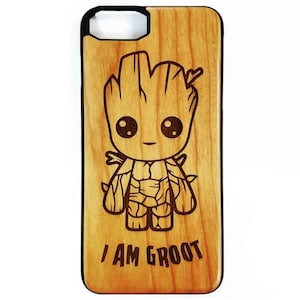 Puede incluir: Una funda de teléfono de madera con una imagen grabada con láser de un personaje de dibujos animados de Groot de la película Guardianes de la Galaxia. La funda tiene un patrón de veta de madera marrón y el texto "I AM GROOT" está grabado debajo del personaje.