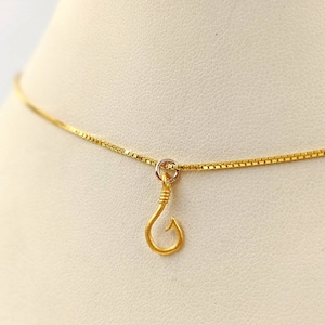 May include: A gold chain necklace with a small gold fish hook pendant.