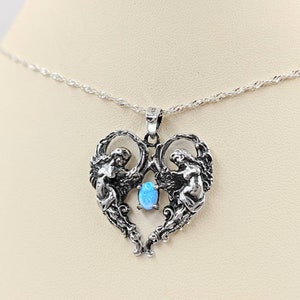 May include: A silver necklace with a heart-shaped pendant featuring two angels with wings and a blue opal gemstone in the center.
