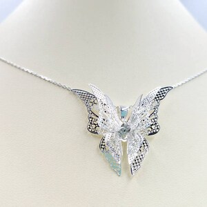 May include: A silver necklace with a delicate butterfly pendant. The butterfly is made of intricate filigree work and has a slightly iridescent finish.