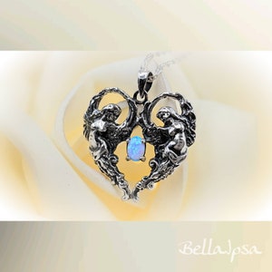 May include: A silver heart-shaped pendant with two angels on either side of a blue opal gemstone. The pendant is on a silver chain.