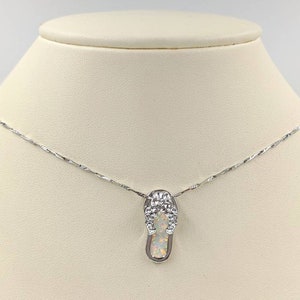 Puede incluir: Un collar de cadena de plata con un colgante de chancla de plata con una piedra de ópalo blanco.