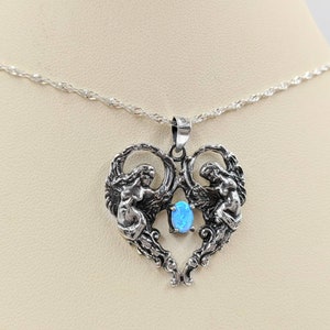 May include: A silver necklace with a heart-shaped pendant featuring two angels and a blue opal gemstone.