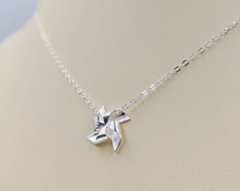 May include: A silver necklace with a delicate chain and a star-shaped pendant. The pendant is made of twisted silver and has a textured surface.