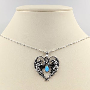 May include: A silver necklace with a heart-shaped pendant featuring two angels with wings and a blue opal gemstone in the center.
