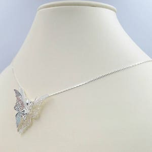 May include: A silver necklace with a delicate butterfly pendant. The butterfly is made of intricate filigree work and has a slightly iridescent finish.